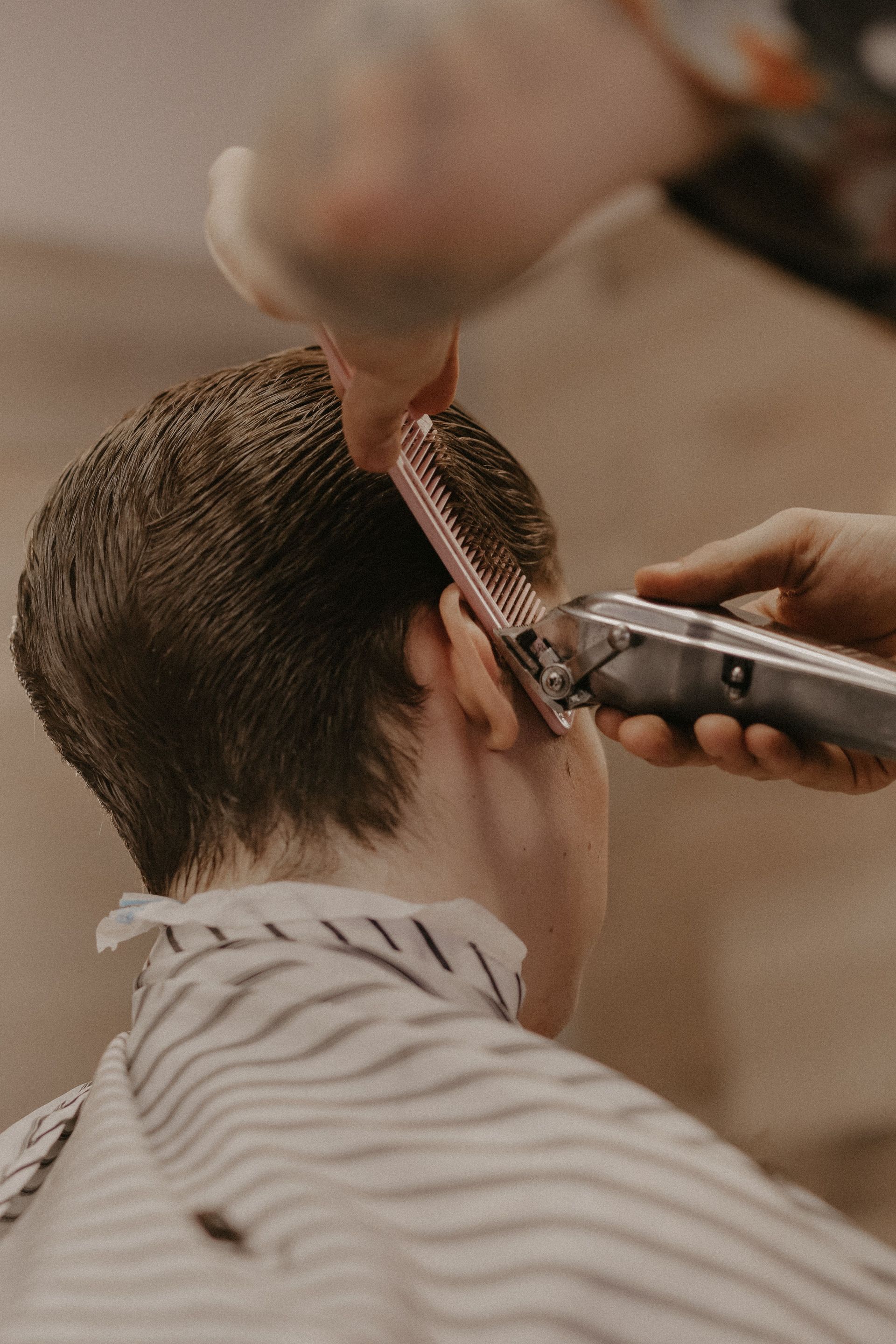 Close-up of a man getting a precise haircut, showcasing grooming tools in a barber shop.
